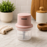Nirogin Rechargeable Vegetable Chopper with pink lid and transparent bowl on kitchen counter.